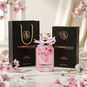 The Fresh Bloom By The Grab perfume bottle is set in a floral soft pink background with matching perfume packaging box.